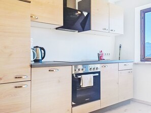 Una cocina moderna con armarios de madera, una estufa negra y un ventanal con vistas.