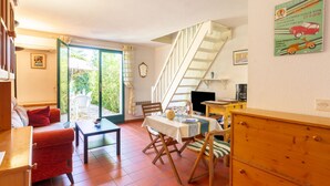 Ein gemütliches Wohnzimmer mit einer Couch, einem Esstisch und einer Treppe.