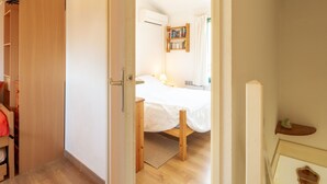 Ein Schlafzimmer mit einem hölzernen Bett, einem Nachttisch, einem Kleiderschrank und einem Regal mit Büchern.