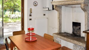 A kitchen with a stone fireplace, a dining table, chairs, and a view of the outside.