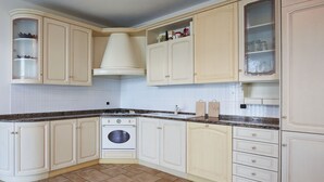Een keuken met witte kastjes, een fornuis en een spoelbak.