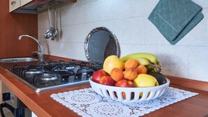A kitchen with a gas stove, sink, and a bowl of fruit on the counter.
