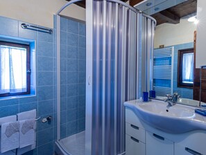 Ein Badezimmer mit Dusche, Waschbecken und Fenster.
