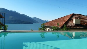 A swimming pool with a mountain backdrop, a building with a tiled roof, and a clear sky.