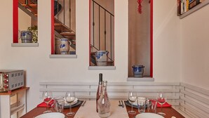 Een eethoek met een tafel gedekt voor vier personen, een fles wijn en een rode decoratieve versiering.