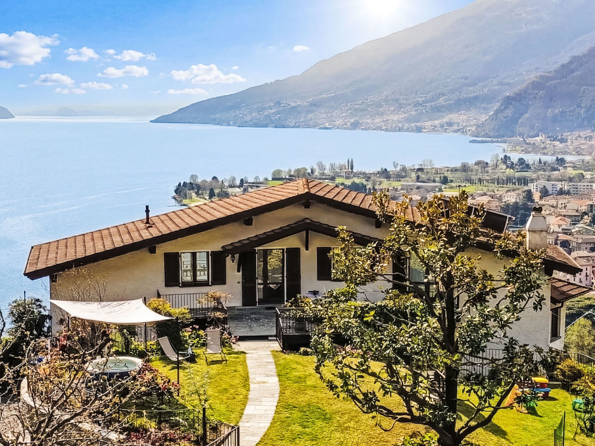 Uma casa com um pátio, uma piscina pequena e vista para um lago e montanhas.
