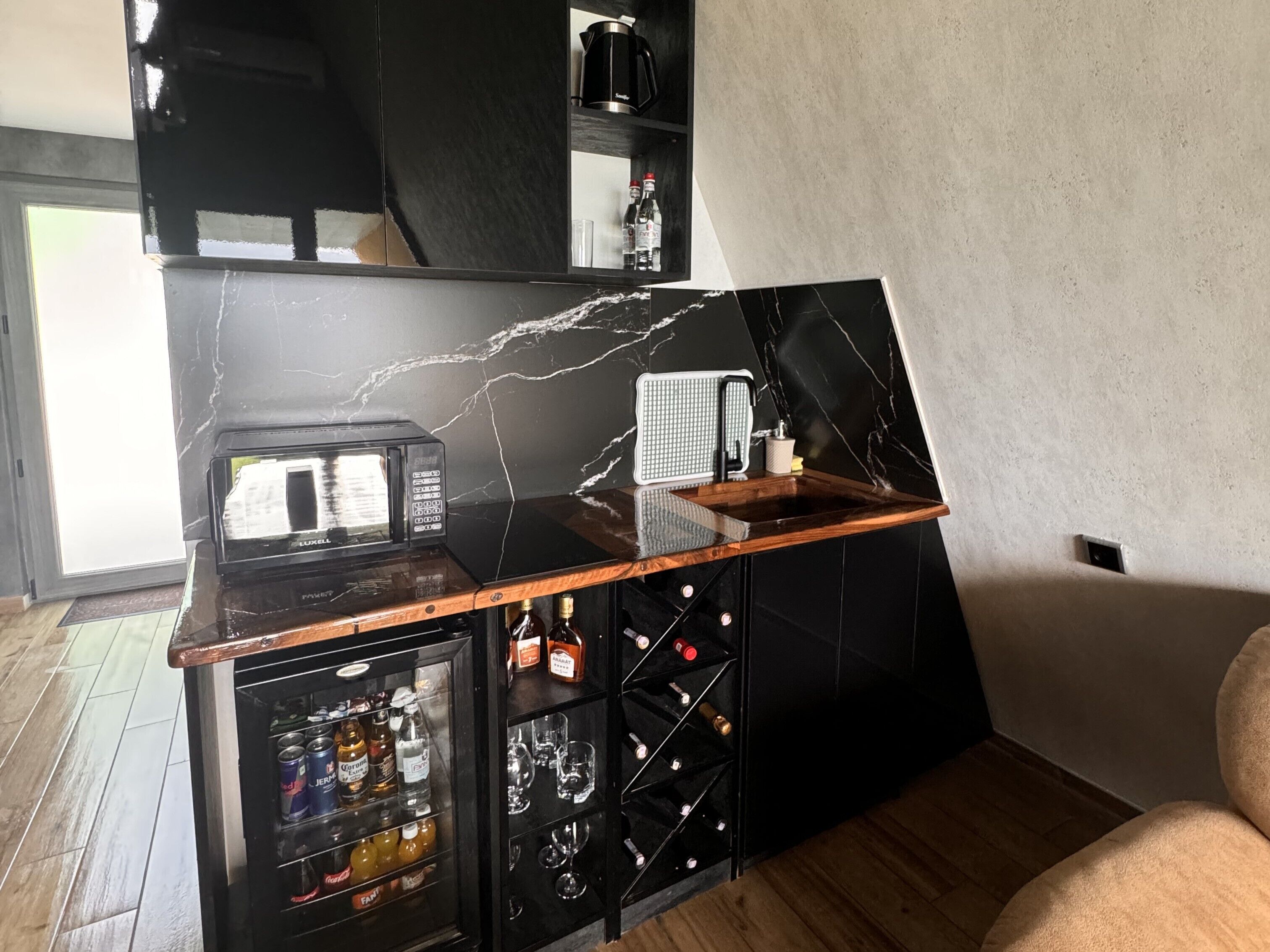 Een moderne keuken met een zwarte marmeren spatwand, een magnetron, een koffiezetapparaat en een wijnrek.