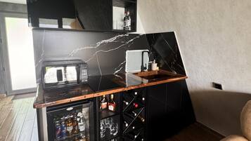 Een moderne keuken met een zwarte marmeren spatwand, een magnetron, een koffiezetapparaat en een wijnrek.