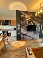 Una cocina moderna con protector contra salpicaduras de mármol, vinoteca empotrada y televisor de pantalla plana montado en la pared.