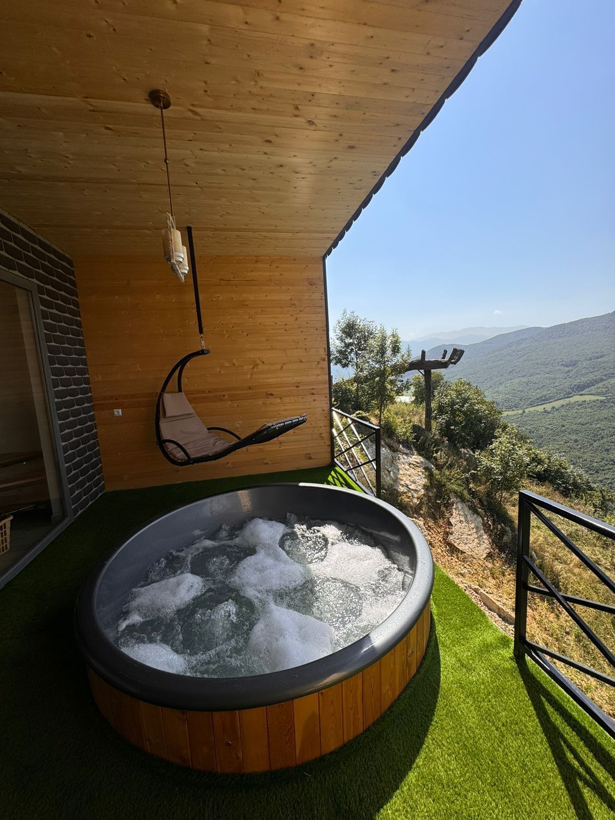 A hot tub on a wooden deck with a view of a mountainous landscape.