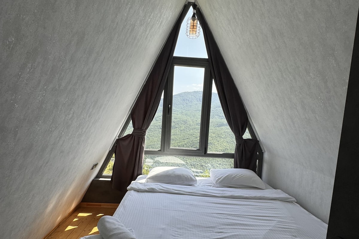 A bedroom with a bed, a window, and a view of the outdoors.