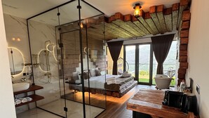 A modern bathroom with a glass partition, a wooden bench, and a large window overlooking a scenic view. - Lost in Sky (Yenokavan)