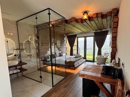 Un baño moderno con separador de vidrio, banco de madera y ventana grande con vistas panorámicas.