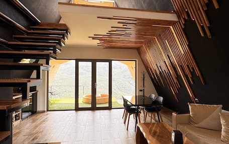 A modern interior with a wooden staircase, a dining area, and a large sliding glass door leading to a garden.