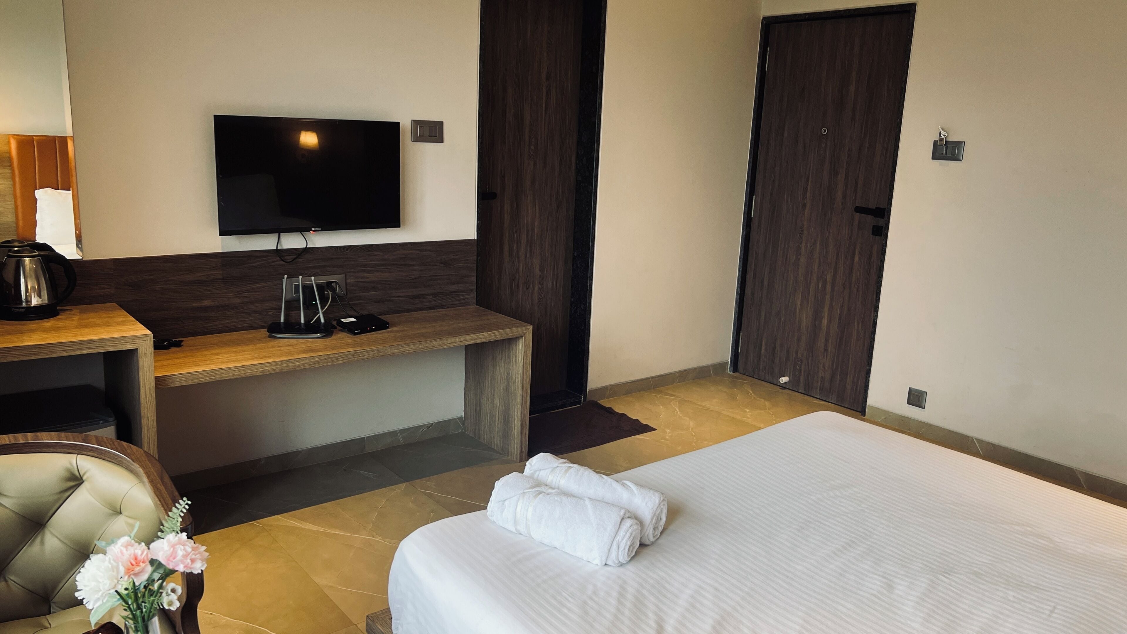 Une chambre d’hôtel comprenant un lit, un bureau avec un téléviseur à écran plat, une machine à café et une chaise.