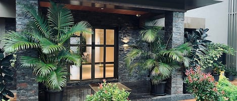 Un edificio moderno con fachada de piedra, ventanas amplias y plantas en macetas.