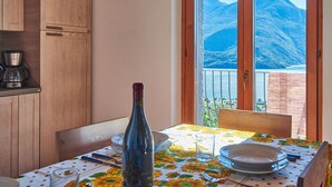 A dining area with a table set for two, a bottle of wine, and a coffee maker on the counter.