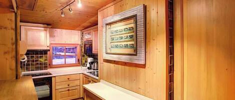 Eine Holzküche mit Backofen, Spüle und einem Fenster mit Blick ins Freie.