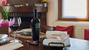 Una mesa de comedor preparada con copas de vino, una botella, un sacacorchos y una cesta de pan.