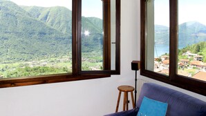 Una habitación con un amplio ventanal que ofrece vistas a un paisaje montañoso y un lago.