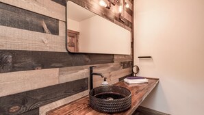 Une salle de bain avec un meuble-lavabo en bois, un lavabo rond et un miroir.