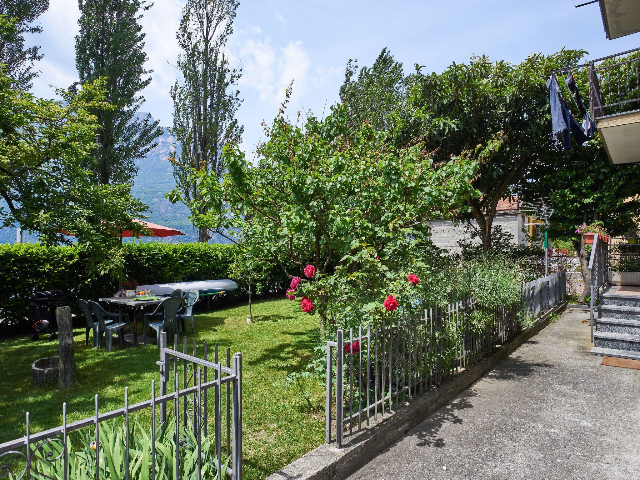 A garden with a metal fence, a table, and chairs.