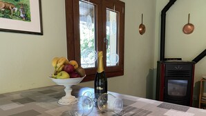 Une table à manger avec un panier de fruits, une bouteille de vin et des verres.
