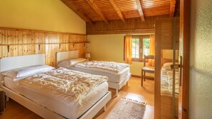 Une chambre dans une cabane en bois, avec deux lits, un plafond en bois et une fenêtre avec des rideaux.