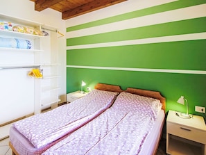 A bedroom with a bed, nightstands, a lamp, a wardrobe, and a green wall. - Baita Checc by Interhome (Cannero Riviera)