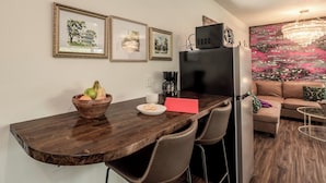 A compact kitchen with a wooden countertop, a black refrigerator, and a dining area with a brown leather couch.