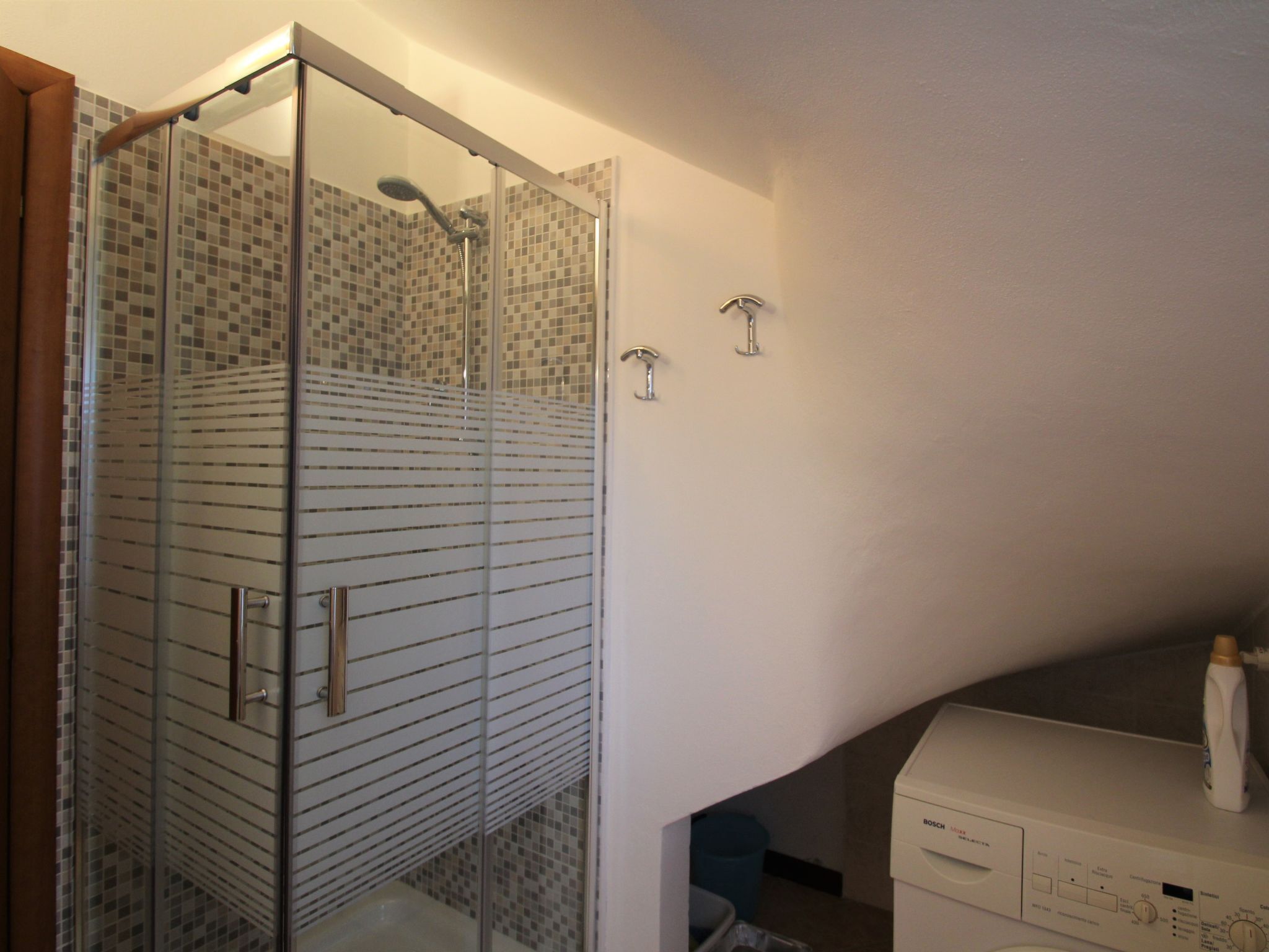 Ein Badezimmer mit Duschkabine, Toilette und Waschbecken, sowie einer Bosch Waschmaschine.