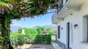 Un patio con mesa y sillas, rodeado de vegetación y vistas a montañas.