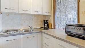 A modern kitchen with white cabinets, a stainless steel sink, and a coffee maker. - Montesole by Interhome (Porto Valtravaglia)