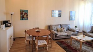 A living room with a round wooden table, two sofas, a coffee machine, and artwork on the walls. - Apartment Roma by Interhome (Porto Valtravaglia)