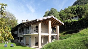 Ein zweistöckiges Haus mit einer überdachten Veranda und einer kleinen Treppe, die zum oberen Stockwerk führt.