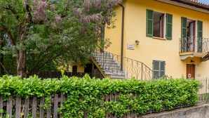 Ein gelbes Gebäude mit Holzzaun, einer Treppe und einem Balkon.