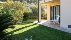 A two-story building with a balcony, a small patio area with a chair, and a well-maintained garden. - Apartment Roseto by Interhome (Cervo)
