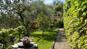 A garden with a wooden cabin, a stone wall, and a gravel path. - Villa Paradiso (DOL192) by Interhome (Dolcedo)