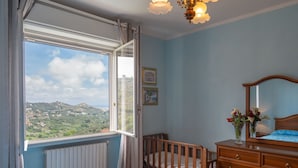 A bedroom with a large window, wooden furniture, and a view of a hilly landscape. - Villa Paradiso (DOL192) by Interhome (Dolcedo)