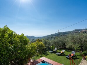 A poolside area with lounge chairs and a wooden deck. - Villa Paradiso (DOL191) by Interhome (Dolcedo)