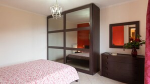Une chambre à coucher avec un lit, une commode, un miroir et un lustre.