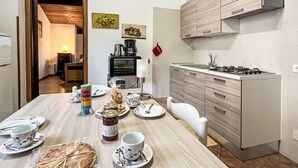 Une cuisine moderne avec une table en bois dressée pour le repas, une cuisinière et des placards.