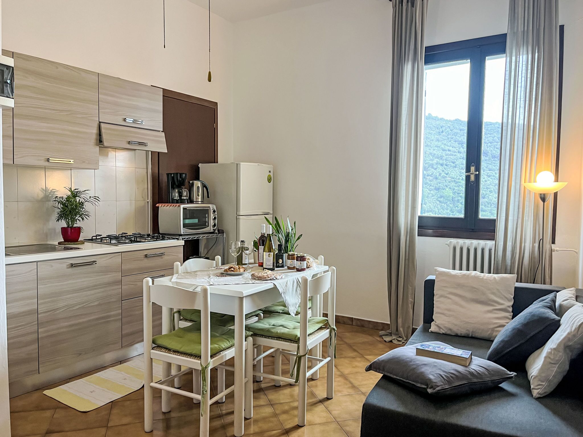 Een ruimtelijk ingerichte leefruimte met kitchenette, eethoek en een zithoek.
