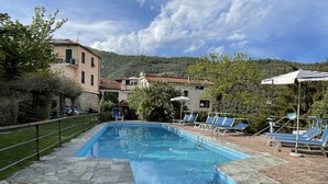 Une piscine rectangulaire, bordée d’un chemin de pierre qui y mène, entourée de chaises longues et avec une chaîne de montagnes en toile de fond.