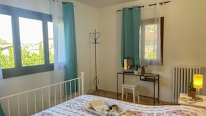 Une chambre à coucher comprenant un lit, un bureau, une chaise, un miroir et un radiateur.