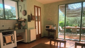 A kitchen with a dining table, a basket of fruit, and a view of the outdoors. - Apartment NISSO by Interhome (Dolcedo)