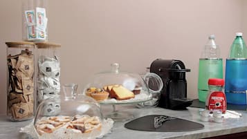 Uma bancada de cozinha com diversos itens, incluindo uma cafeteira, café Nescafe Classic, um bebedouro e alimentos em recipientes de vidro.