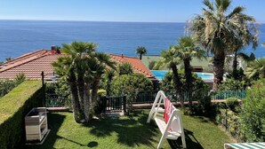 Une terrasse avec un barbecue, une balançoire et une vue sur l’océan.