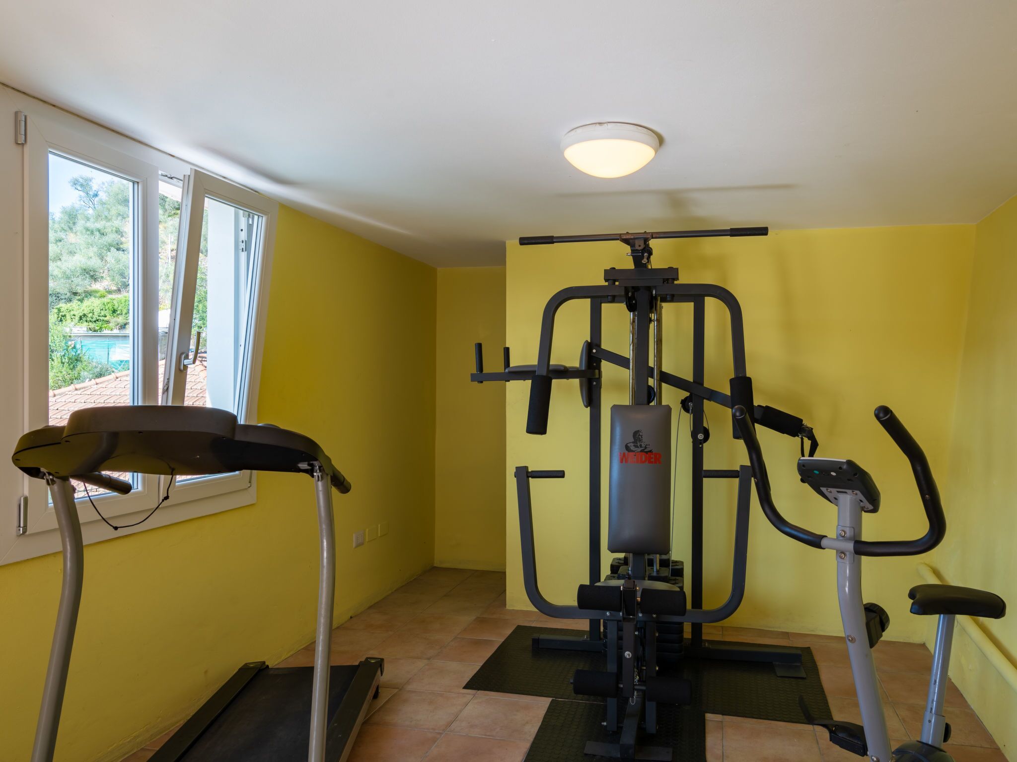 A fitness room with a treadmill, a multi-functional exercise machine, and a stationary bike.