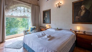 A bedroom with a large bed, two bedside tables, a chair, a window with curtains, and two paintings on the wall. - Villa Carlotta by Interhome (Costigliole d'Asti)
